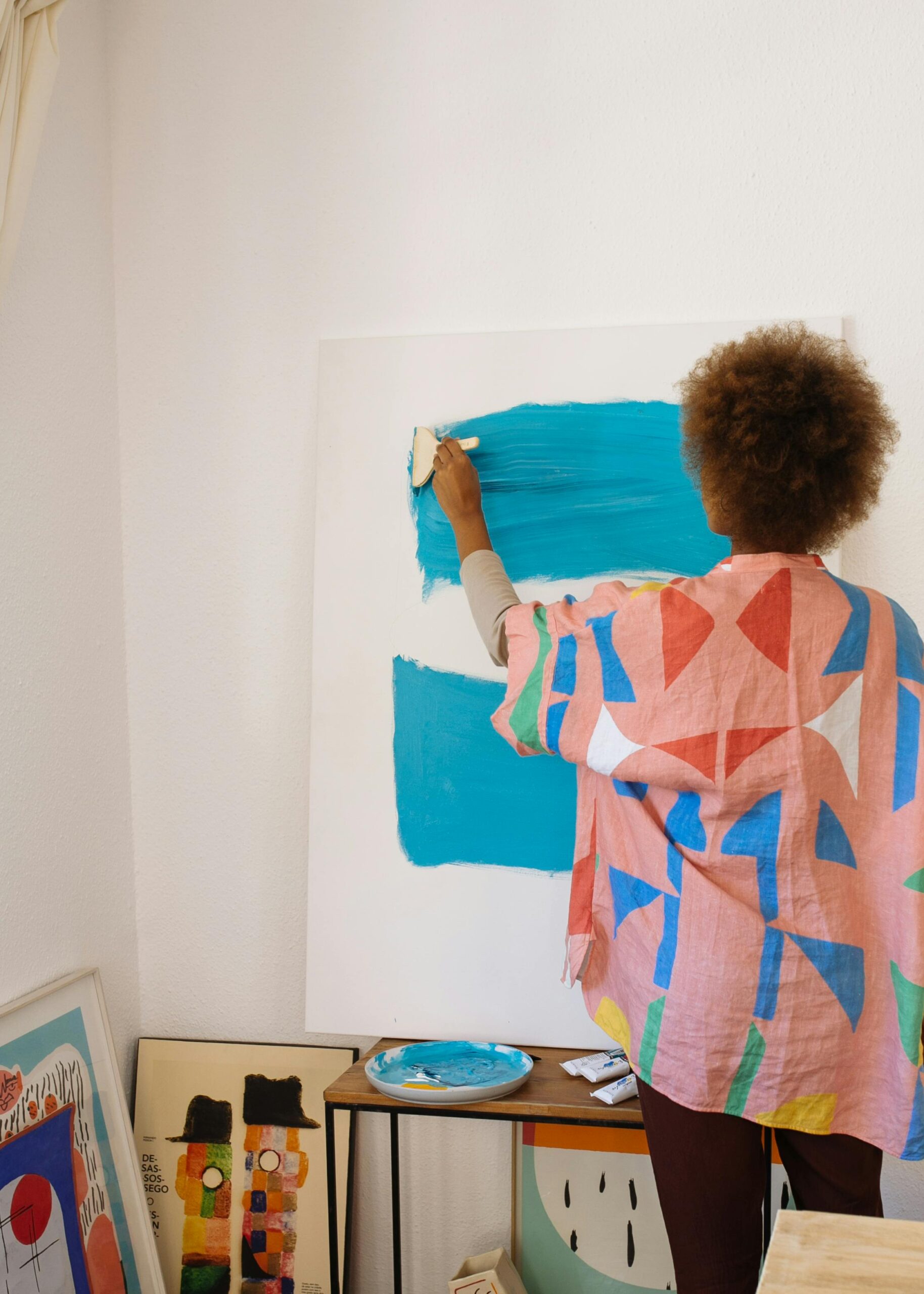 Female artist works on a colorful abstract painting in her art studio, showcasing creativity and skill.